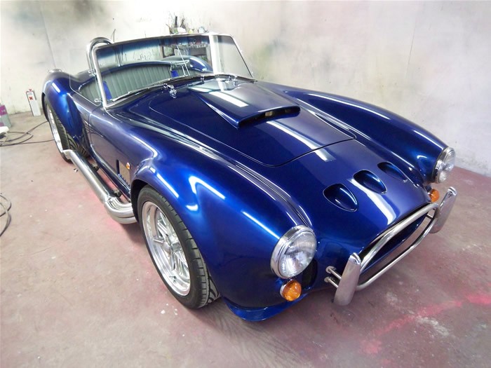 Freshly painted blue Cobra with white stripes inside the spray booth