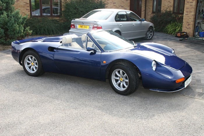 Dark blue sports car with silver stripe parked on a driveway